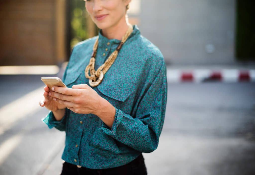 A person holds a phone while looking at the screen.
