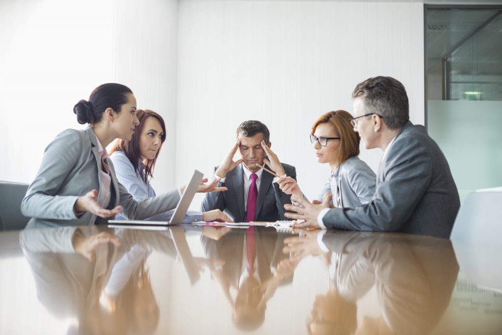 A group is viewing a laptop at a table.