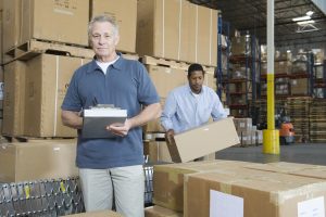 A person stands in a warehouse surrounded by shipping boxes.