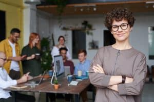A person stands in front of a table with people seated around it.