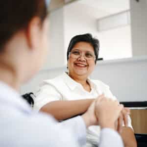 Friendly female doctor tries to support patient, holds her hands