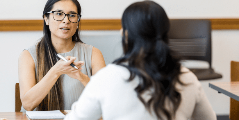 Two colleagues engaged in a feedback conversation, representing modern performance management through regular check-ins and coaching.